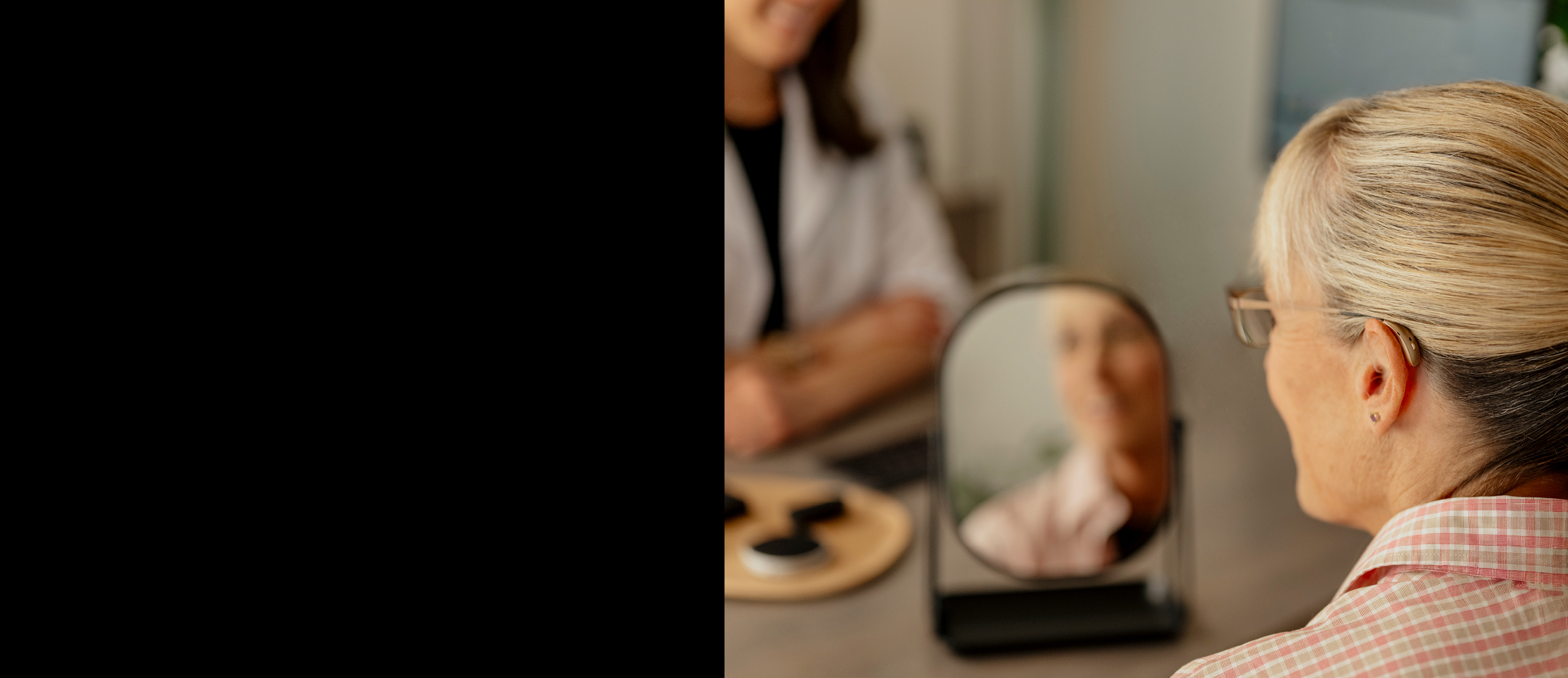 Woman looking in the mirror after being fit with hearing aids.