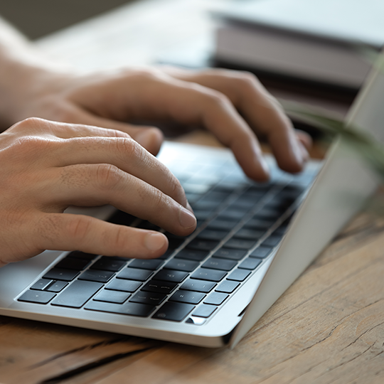 Hands typing on a laptop.